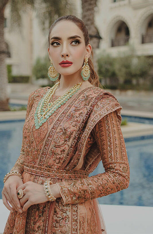 Jahan Ara coral pink ensemble; Pakistani formal dress with intricate embroidery and elegant jewelry.-Side profile of Jahan Ara coral pink ensemble highlighting graceful fit.