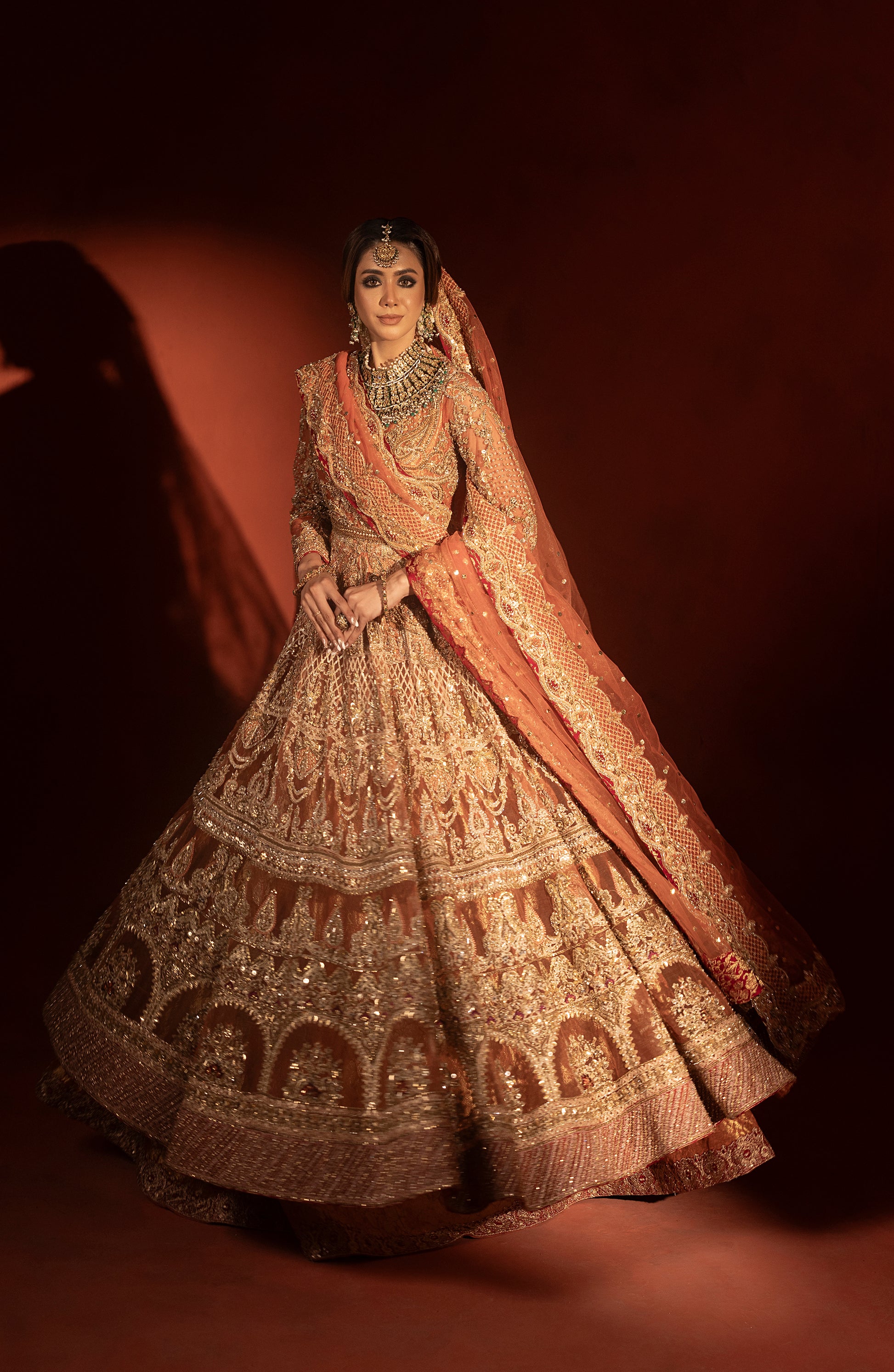 Model showcasing rust orange pishwas lehenga back design