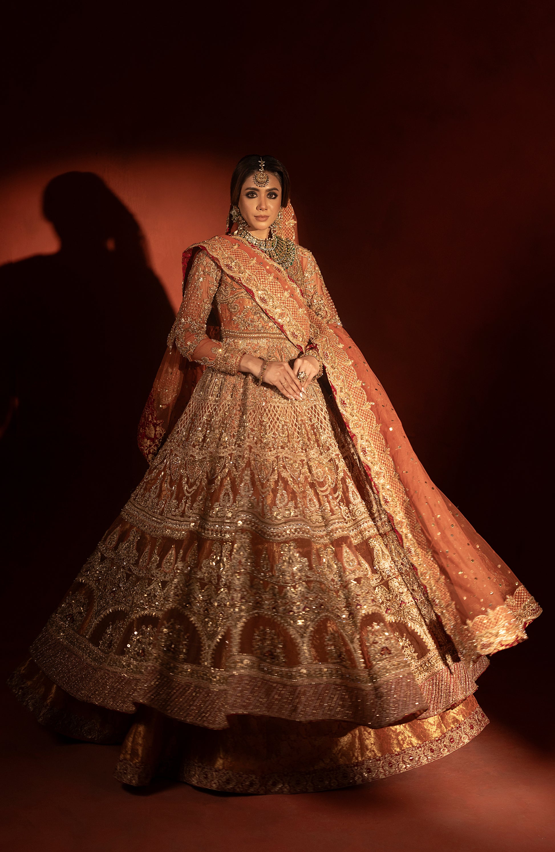 Model wearing rust orange pishwas jamawar lehenga front pose