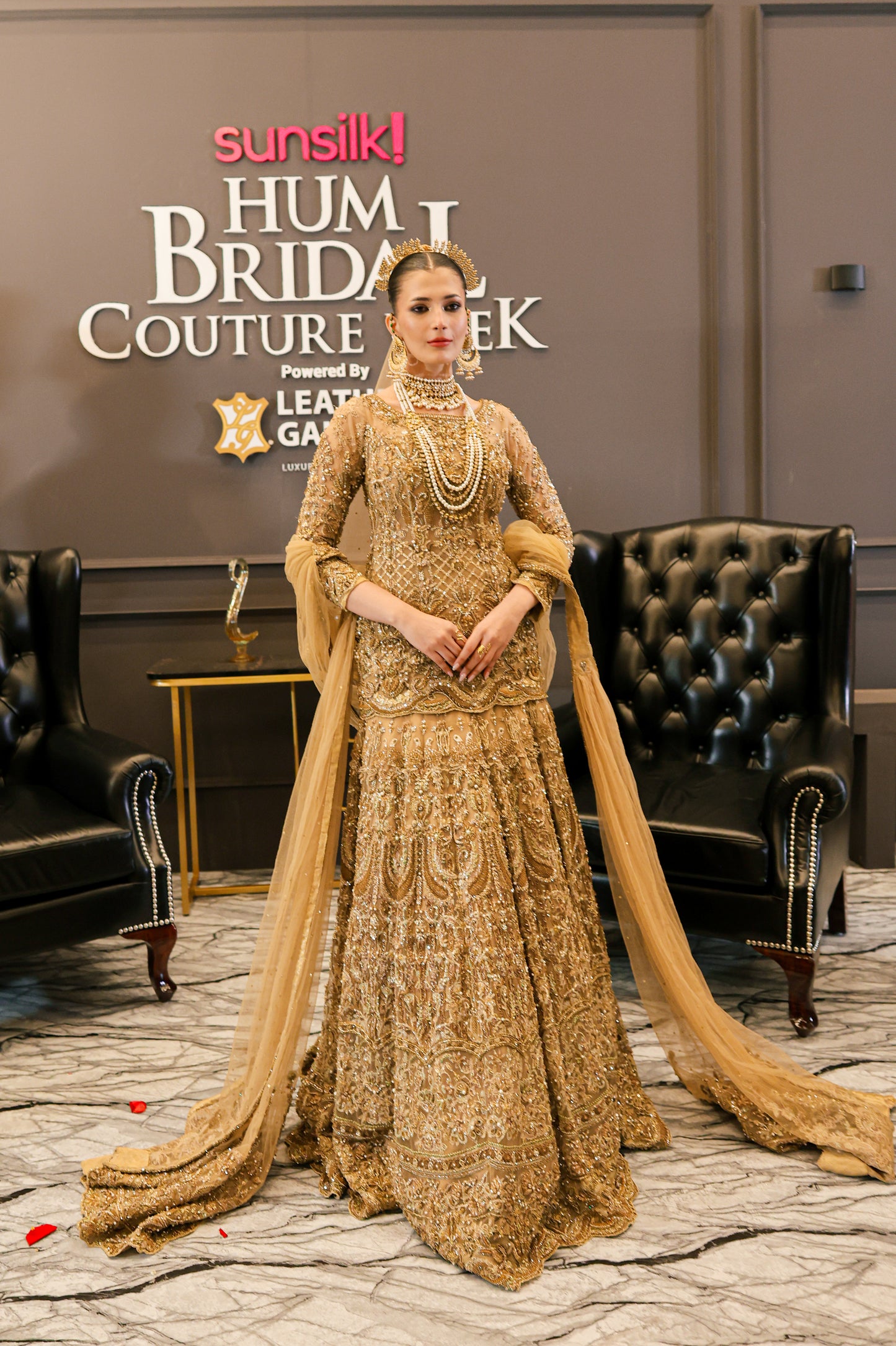 Woman in a gold embroidered traditional outfit at Hum Bridal Couture Week event.
