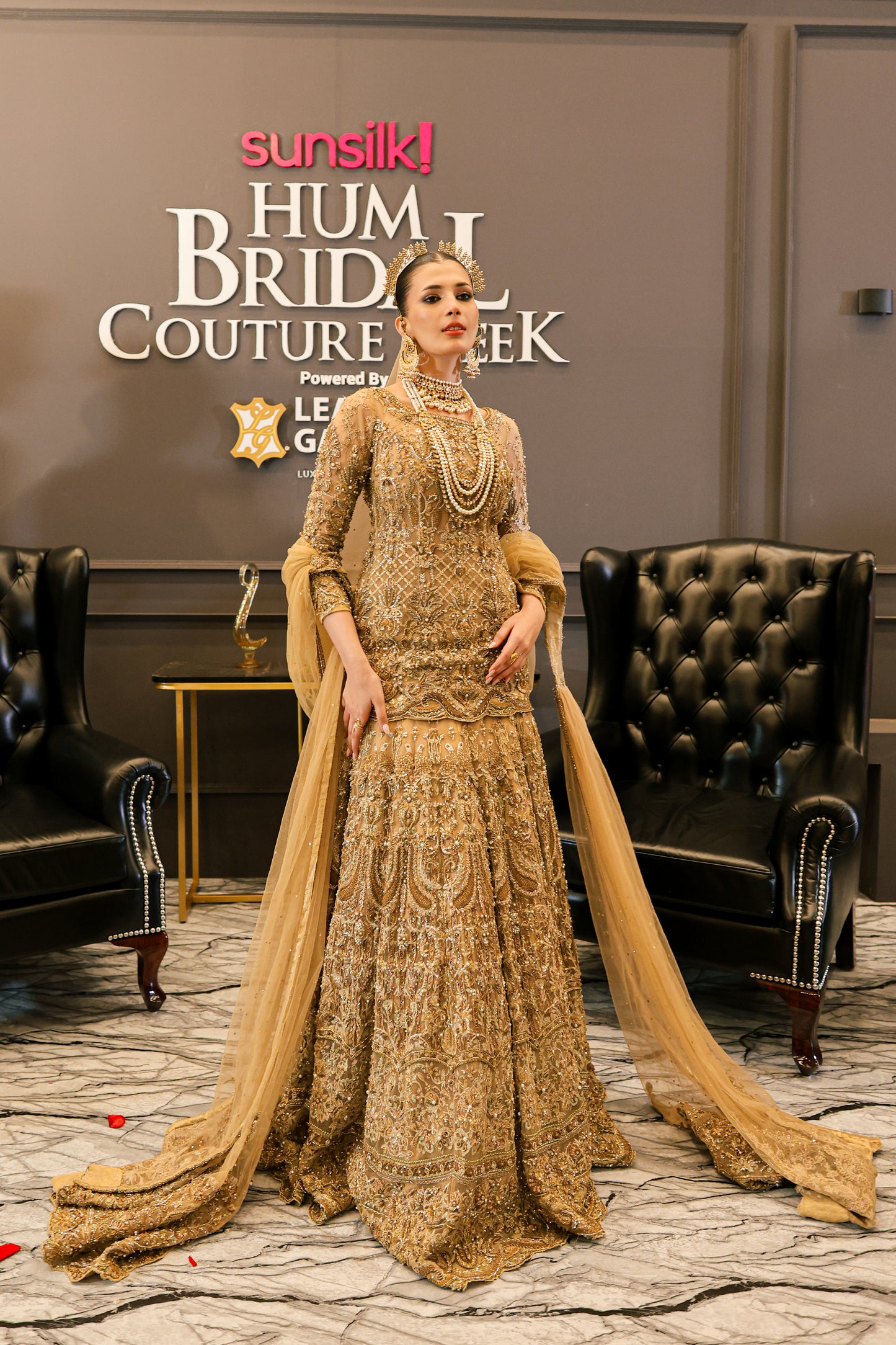 Woman in a gold embroidered traditional outfit at Sunsilk Hum Bridal Couture Week event.