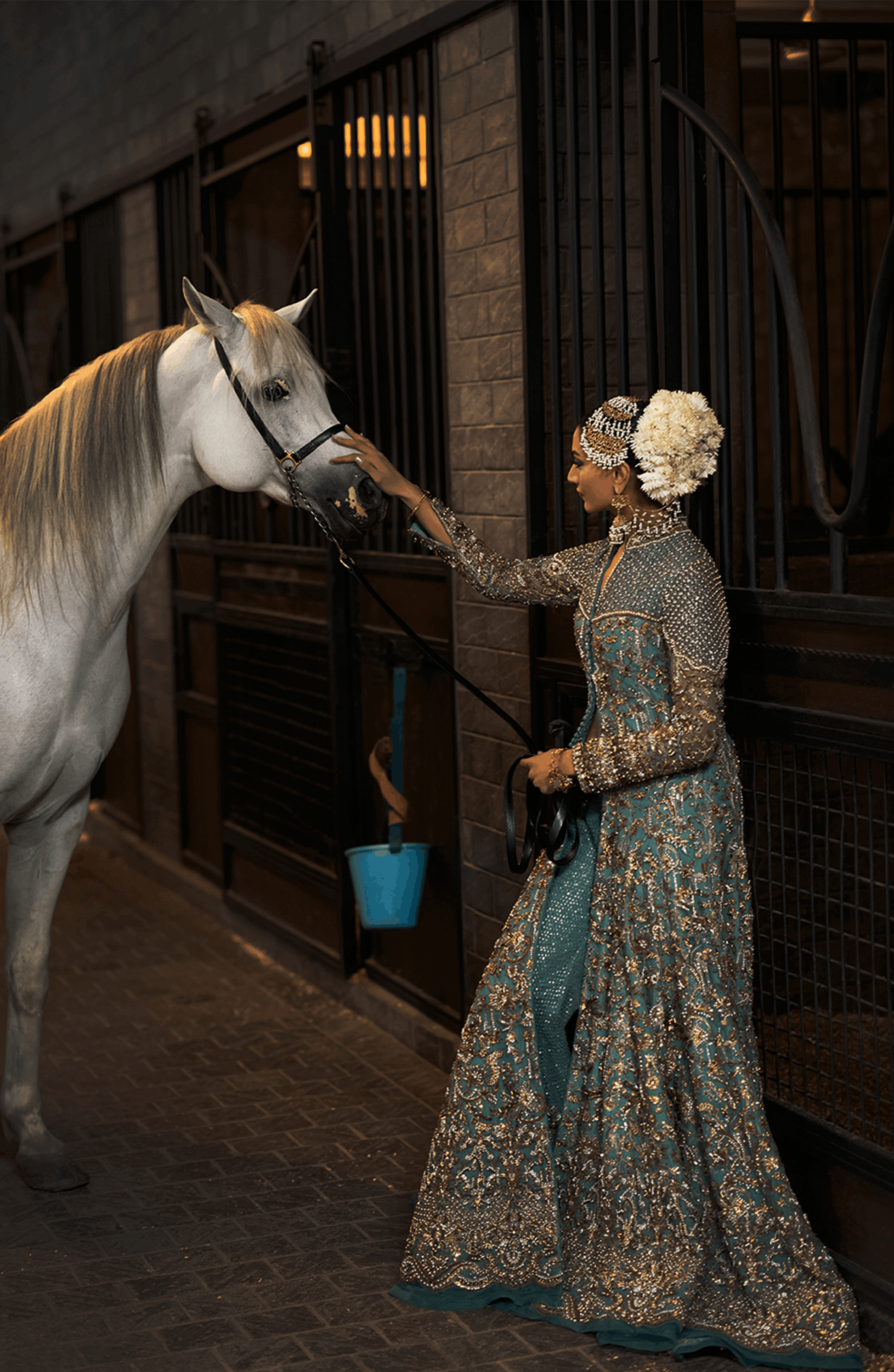 Woman in a patterned dress interacting with a horse in a stable.
