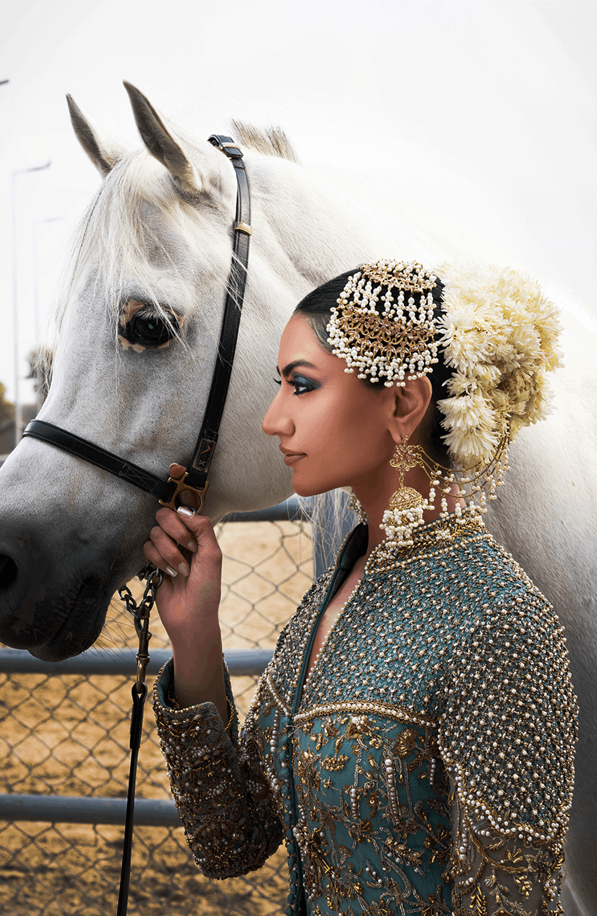 Woman in traditional attire standing next to a white horse