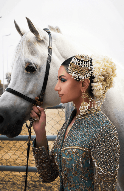 Woman in traditional attire standing next to a white horse