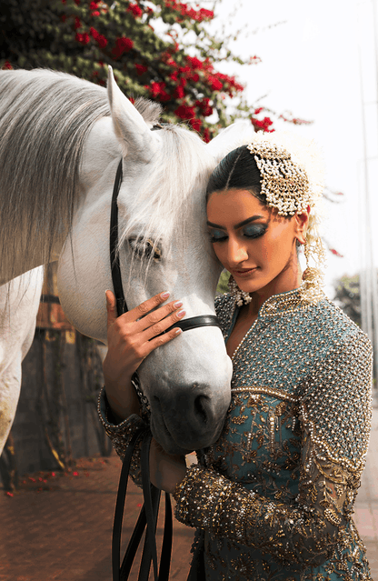 Woman in a sparkling outfit petting a white horse with a decorated background