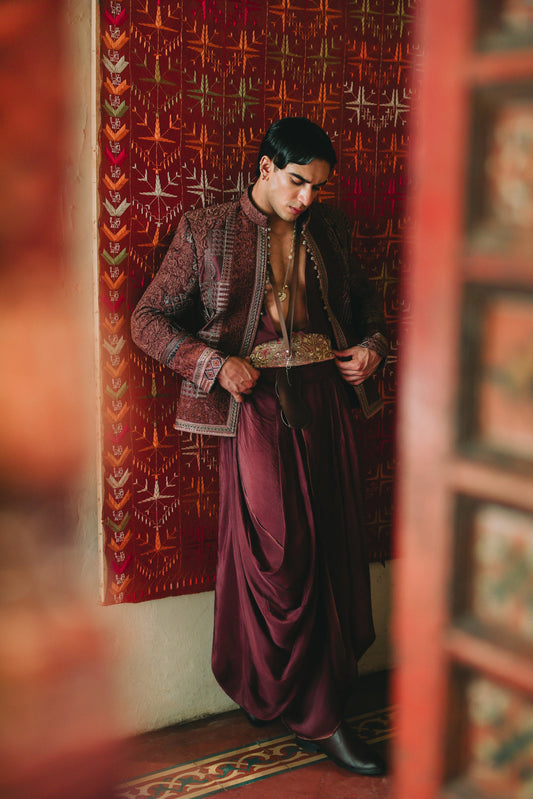 Person in traditional attire standing in a room with decorative walls.