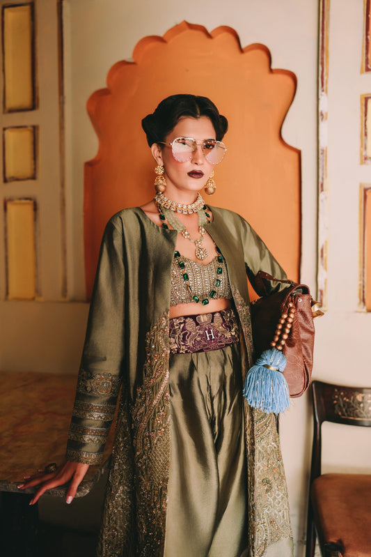 Woman in traditional attire with jewelry and a colorful bag in an ornate room.