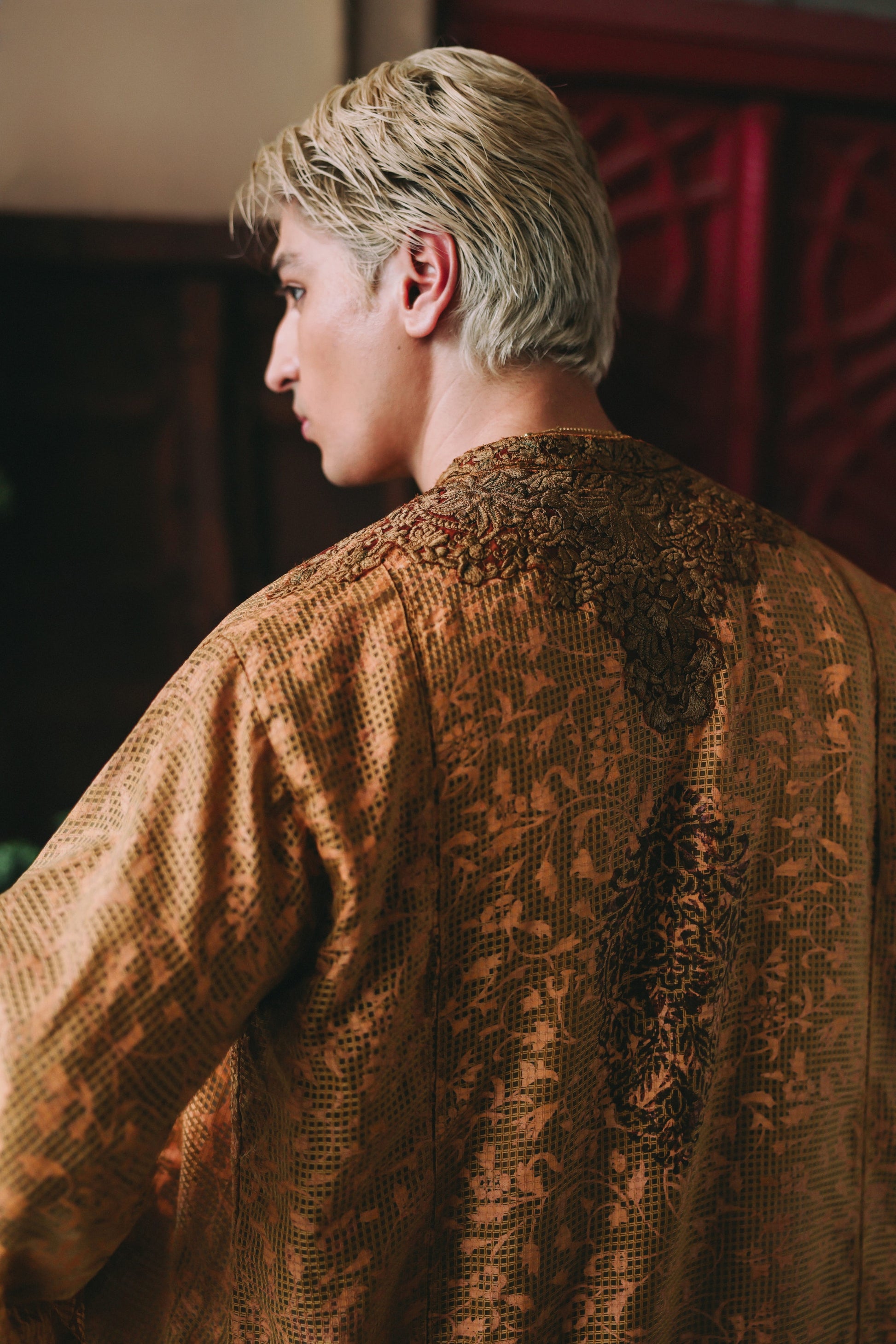 Person wearing a textured brown garment with intricate patterns.