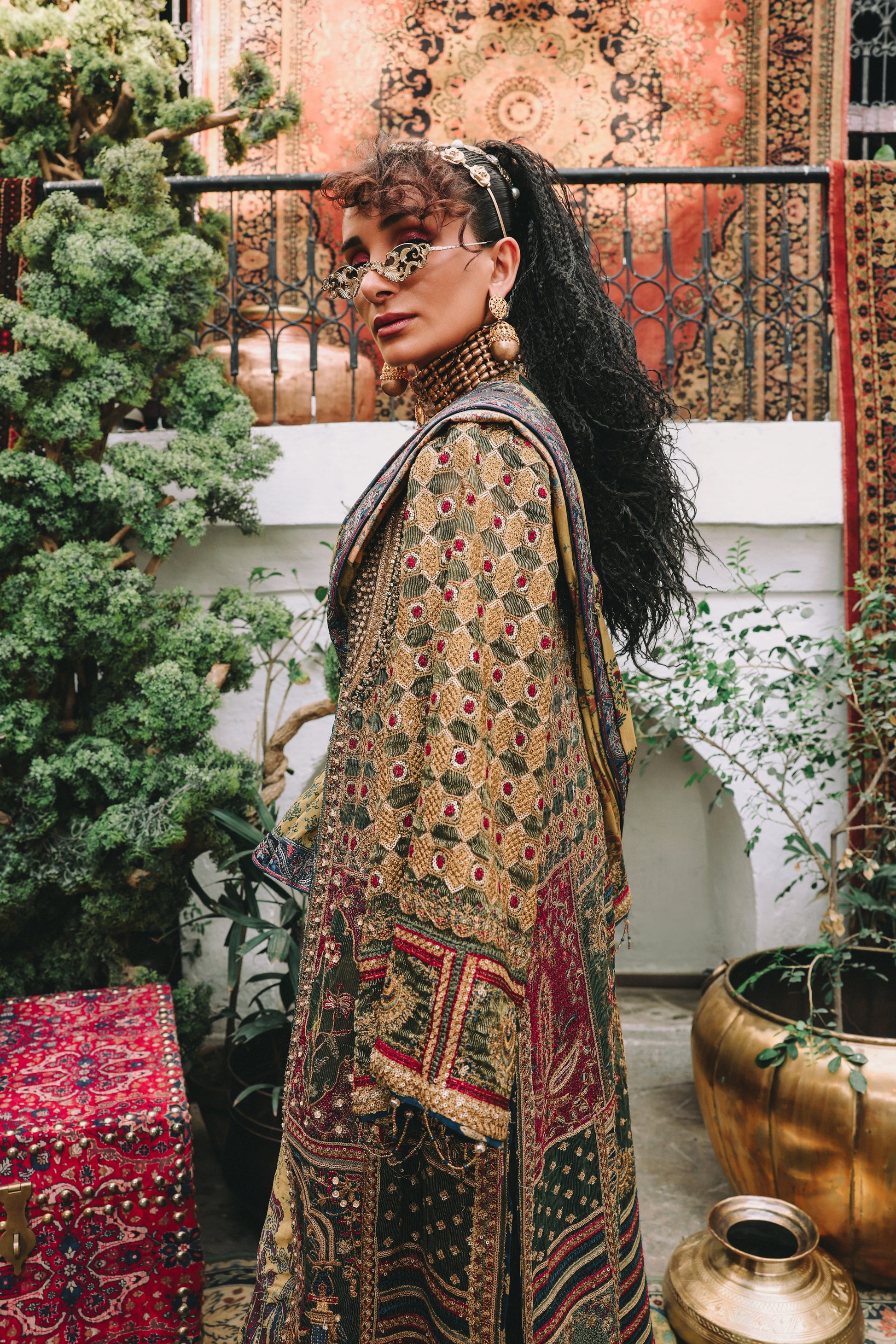 Woman in a patterned outfit standing in an outdoor setting with decorative elements.