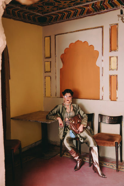 Woman sitting in a room with ornate decor and a colorful wall design.