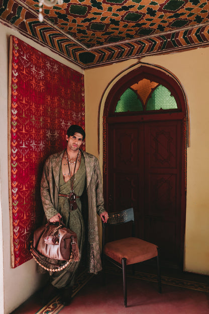 Person in traditional attire standing in a room with ornate ceiling and wall decorations.