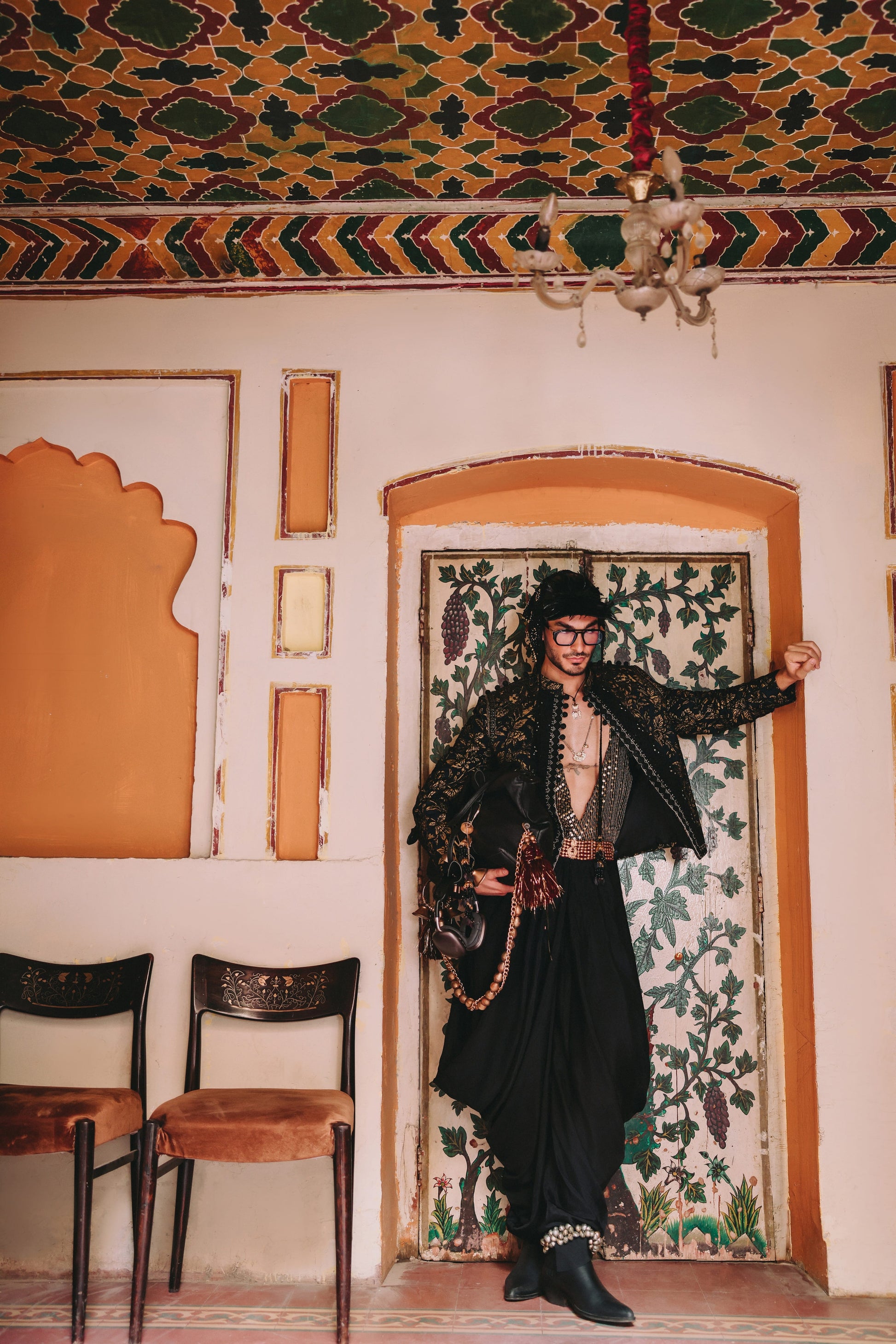 Person in traditional attire standing in a room with ornate walls and ceiling.