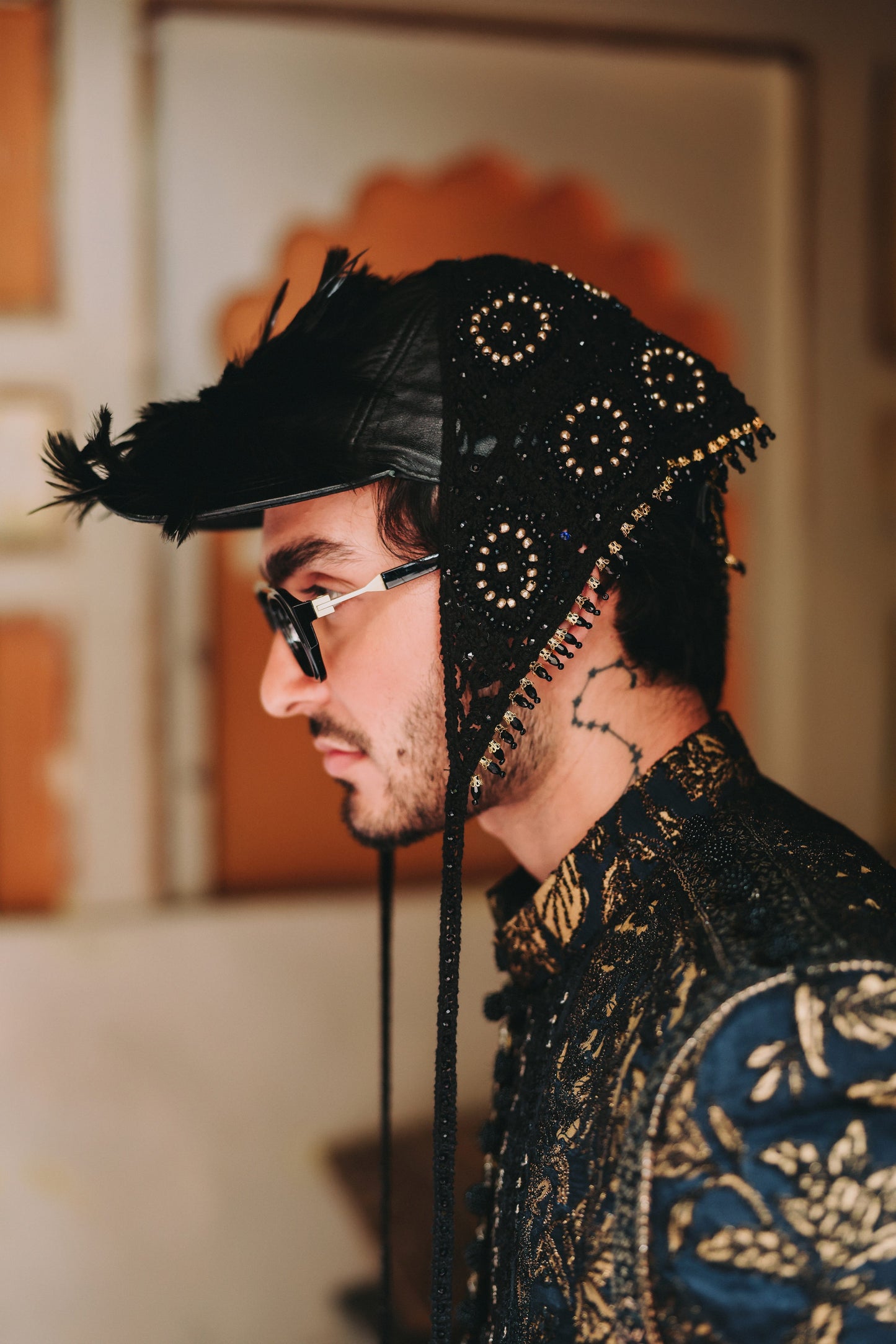 Man wearing a decorative black headpiece with gold accents and a patterned garment.