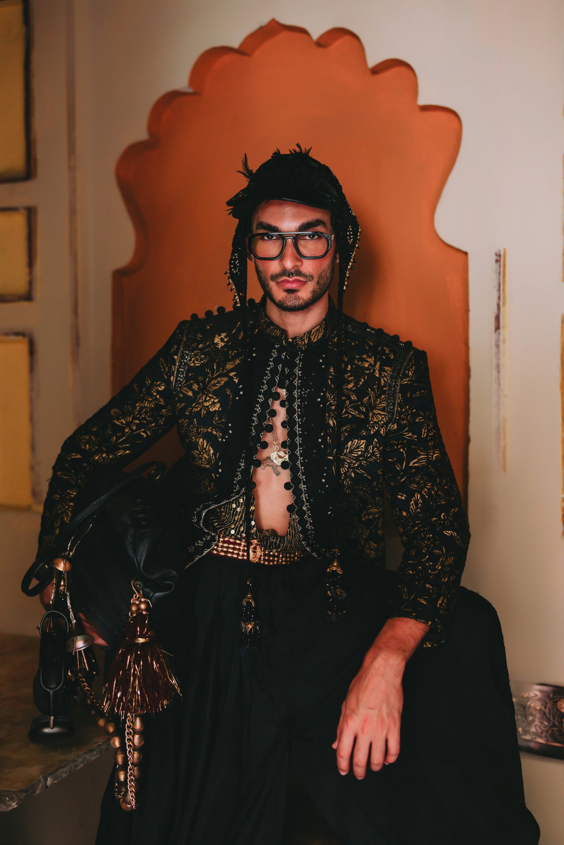 Person wearing a decorative black and gold outfit with a unique chair in the background