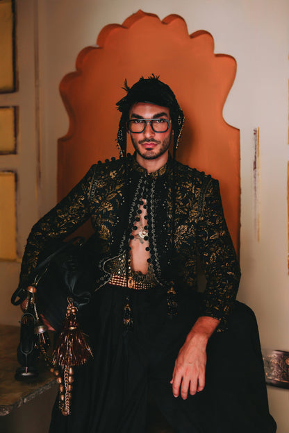 Person wearing a decorative black and gold outfit with a unique chair in the background