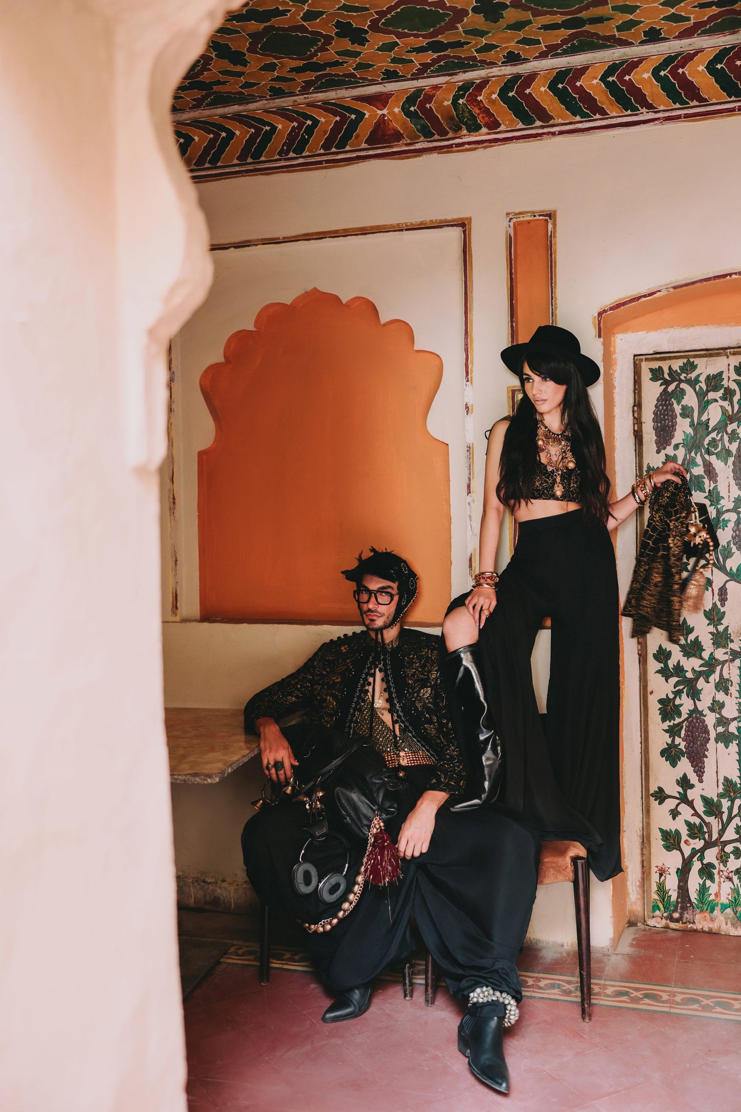 Two people in ornate clothing sitting in a room with decorative walls and ceiling.