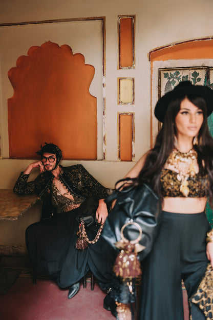 Two people in stylish outfits in a decorative interior setting.