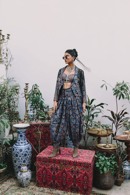 Woman in a patterned outfit standing in a room with plants and decorative items.
