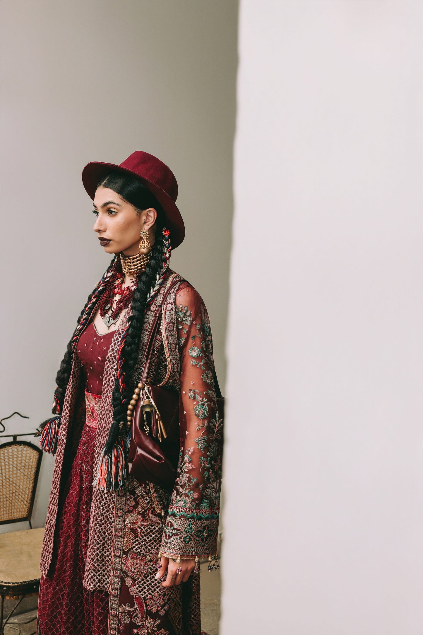 Woman in a patterned outfit with a red hat against a plain background