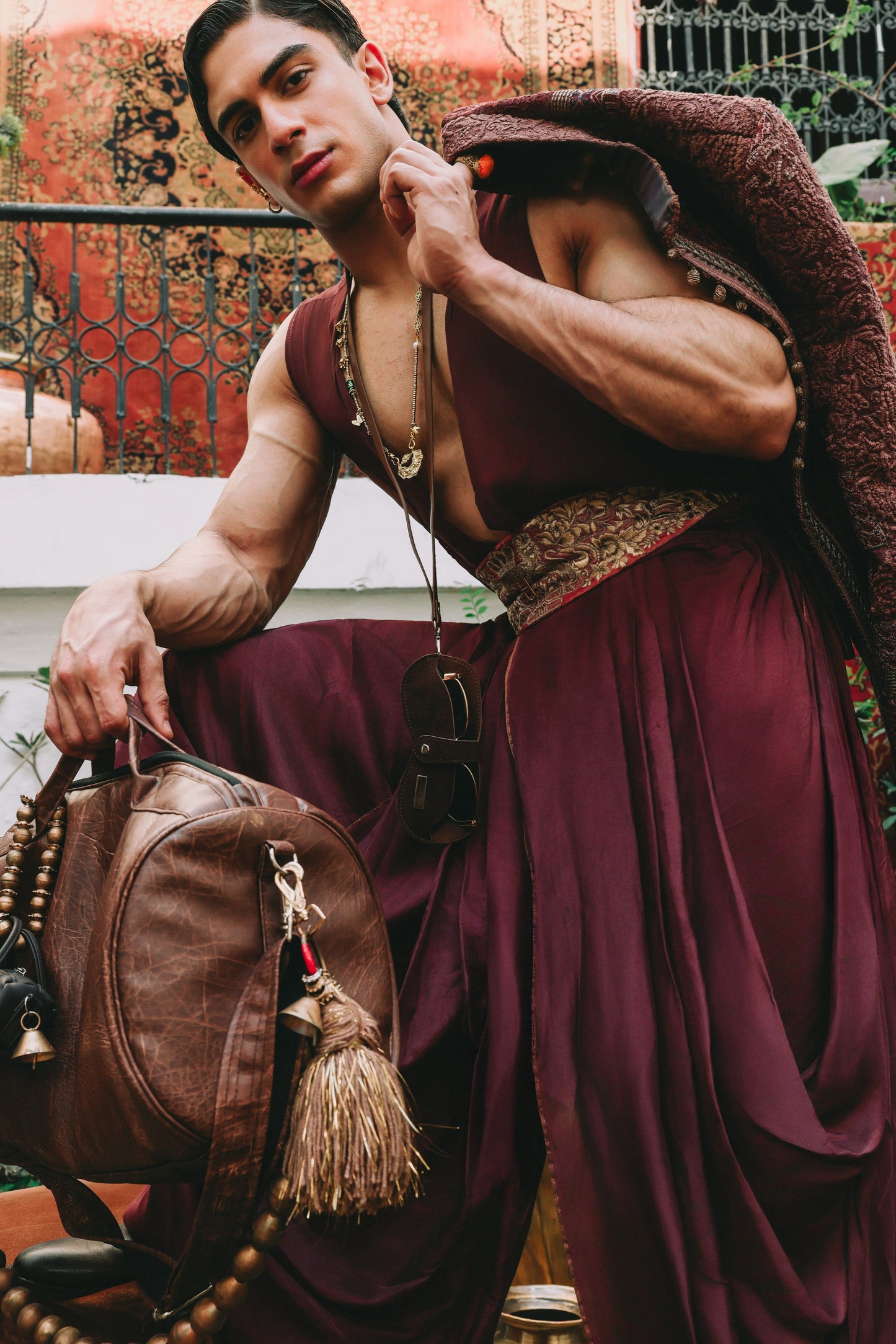 Man in traditional attire holding a leather bag with tassels.