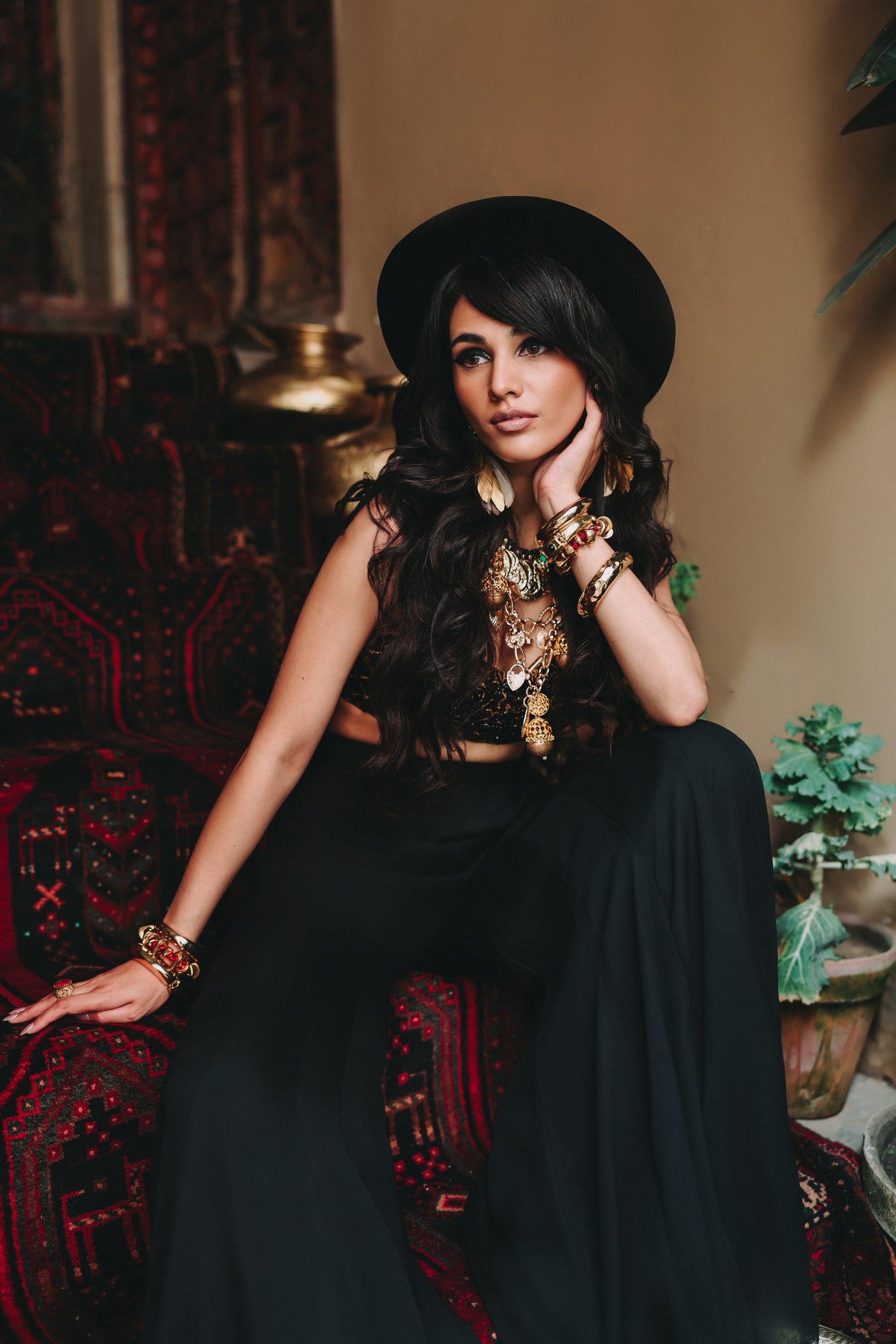 Woman in a black outfit with jewelry sitting on a patterned chair.