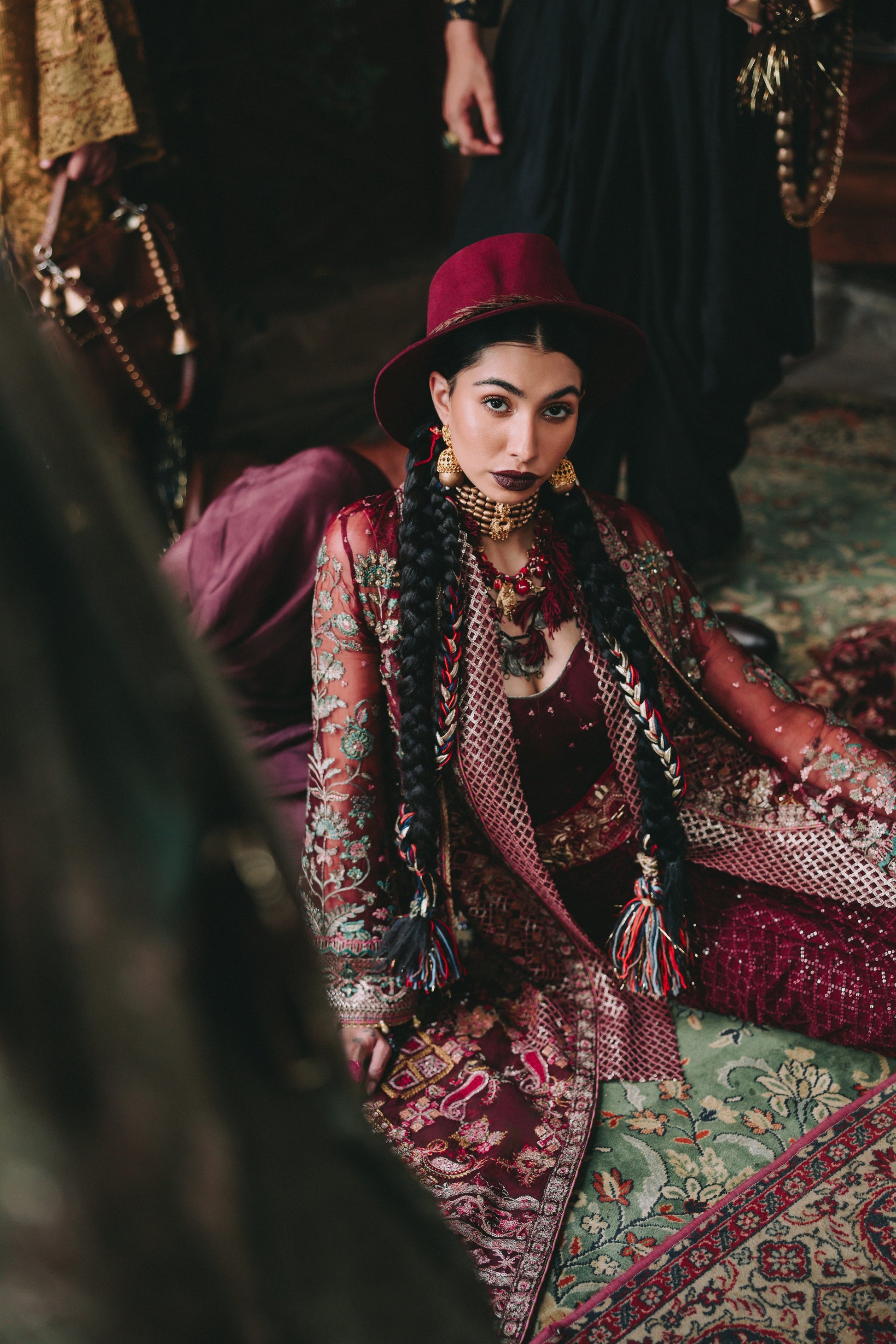 Woman in traditional attire sitting on a patterned rug
