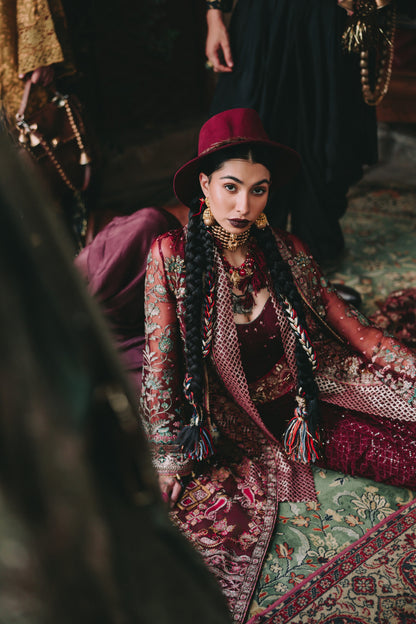 Woman in traditional attire sitting on a patterned rug