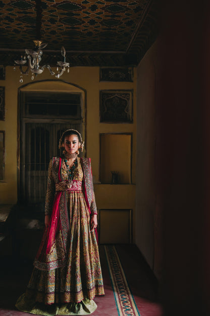 Woman in traditional attire standing in a dimly lit room with ornate ceiling.
