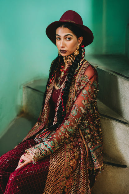 Woman in a patterned outfit sitting on steps with a teal wall background