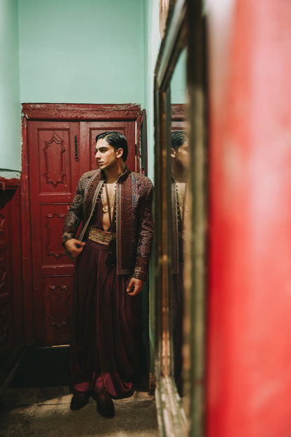Man in traditional attire standing in a room with red and green walls.