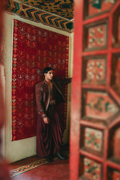 Person in a burgundy outfit standing in a room with ornate red walls and ceiling.