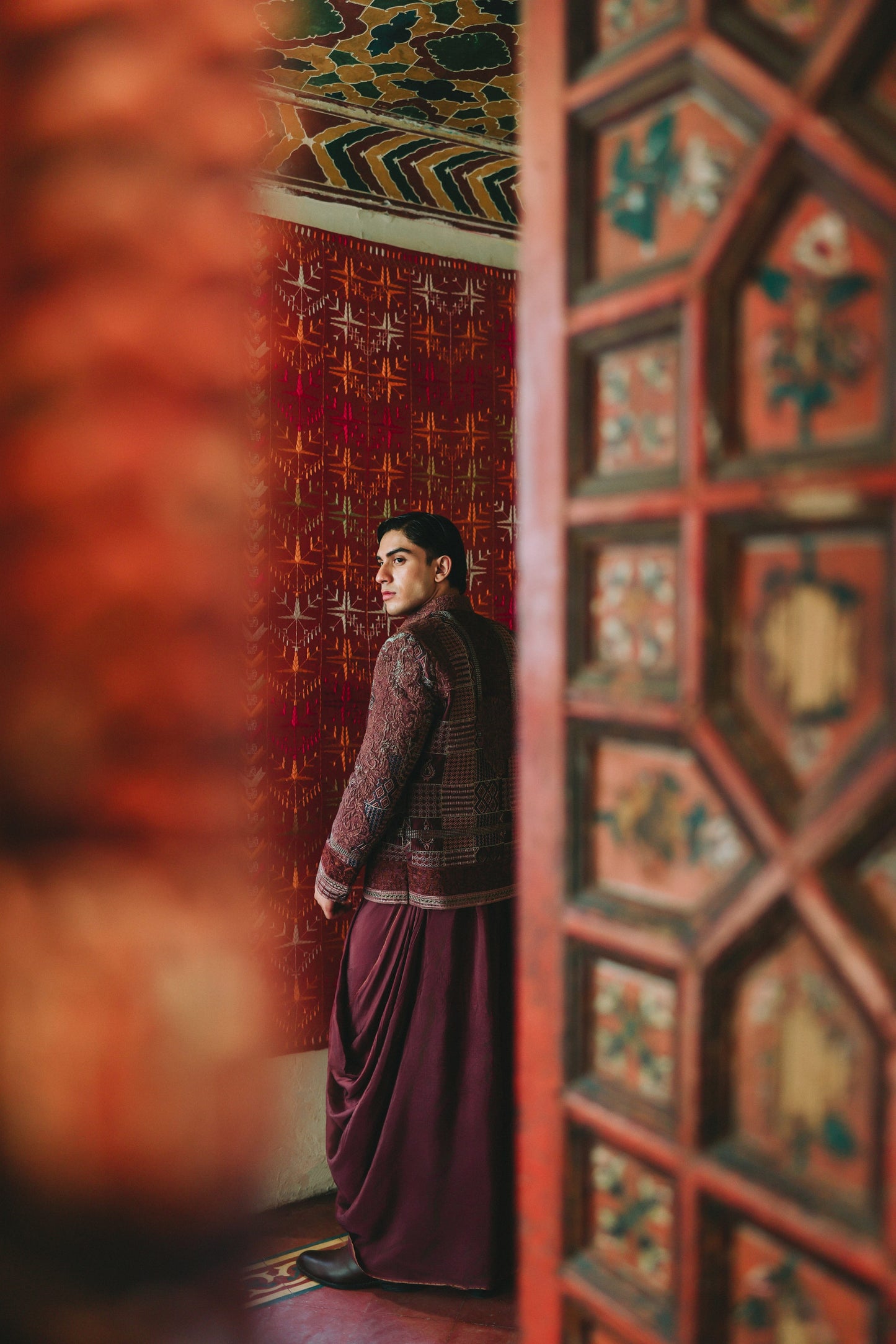 Person standing in a room with ornate red and gold walls.