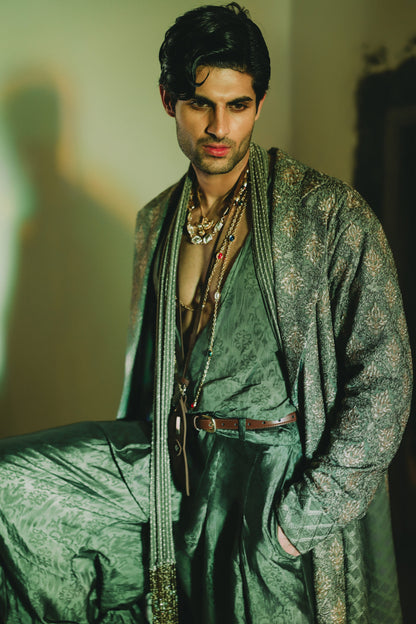 Man wearing a green traditional outfit with intricate patterns