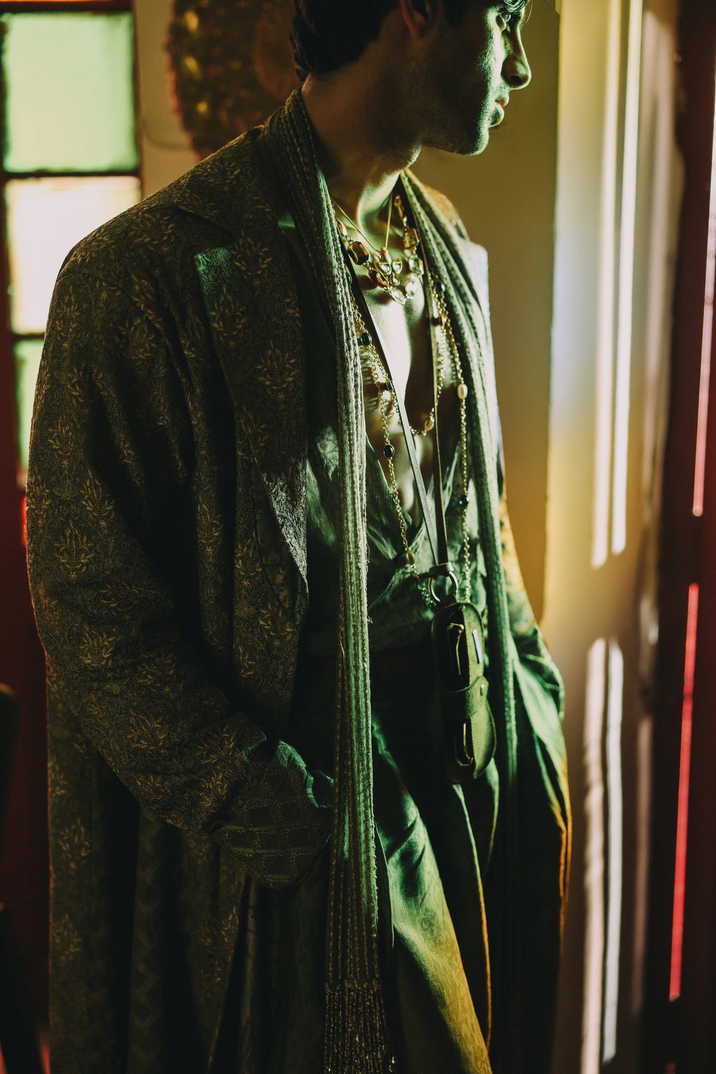 Person wearing a green coat with a patterned scarf in a dimly lit room.