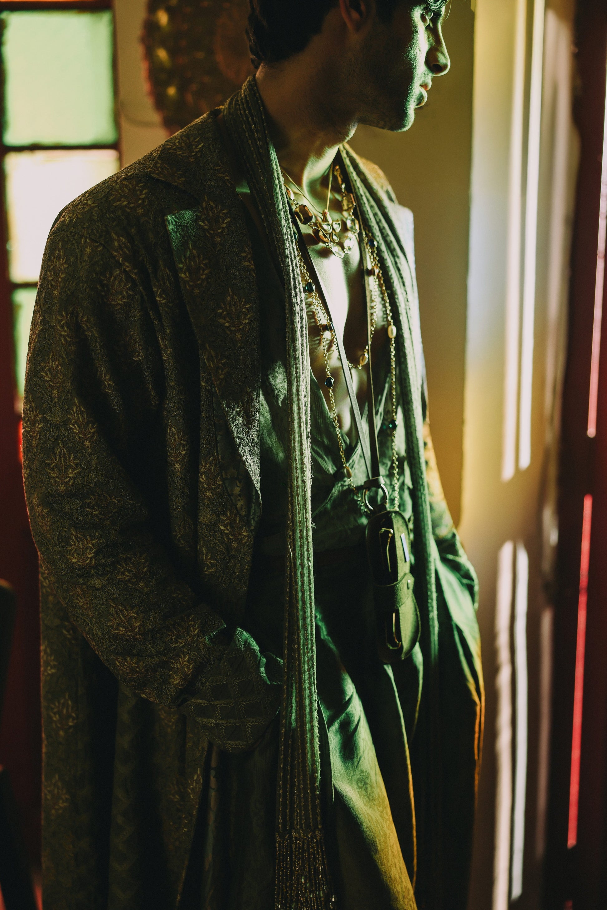 Person wearing a green coat with a patterned scarf in a dimly lit room.