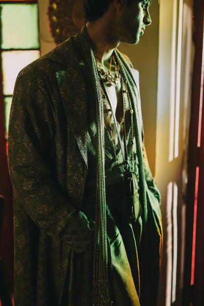 Person wearing a green coat with a patterned scarf in a dimly lit room.