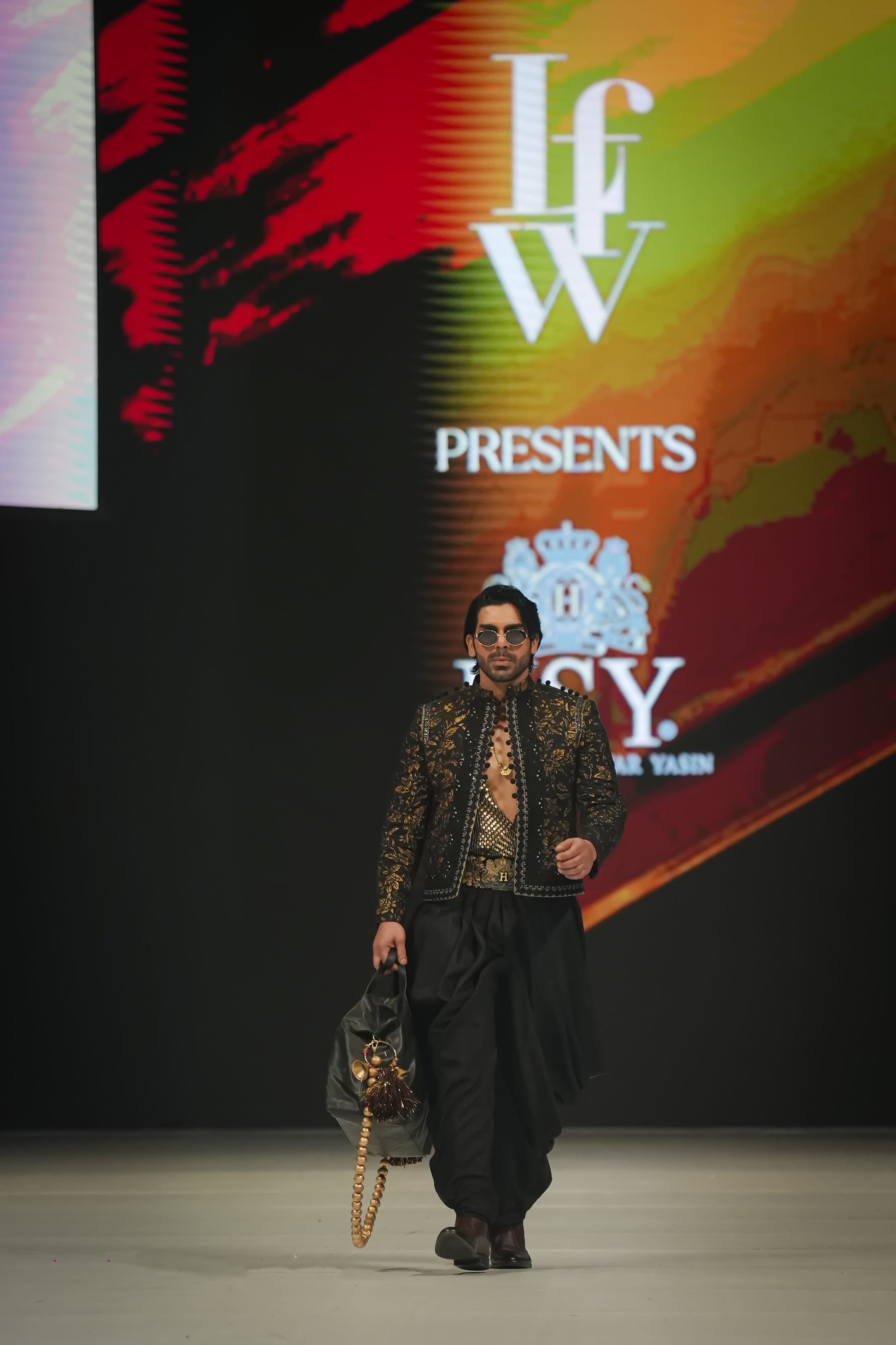Model walking on a catwalk with 'IFW' and 'Ferdy' branding in the background.