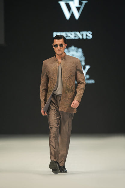 Man walking on a runway wearing a brown suit with sunglasses, against a black background with 'lfW' branding.
