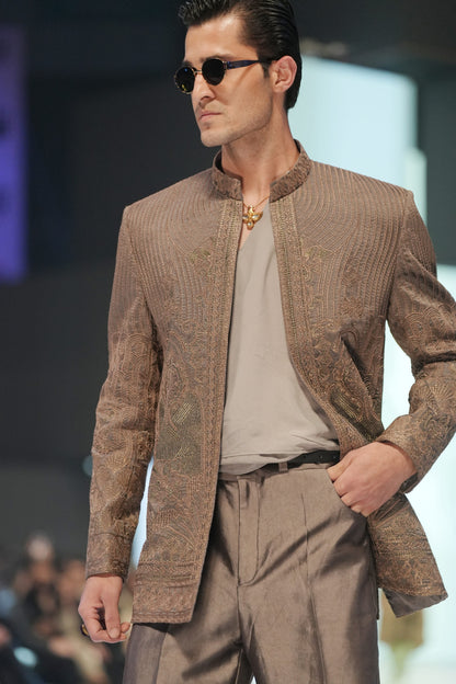 Man wearing a brown textured suit and sunglasses on a fashion show runway.