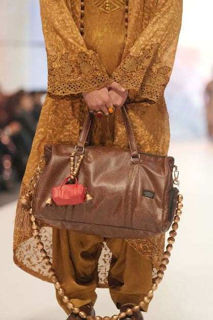 Person holding a brown leather handbag with a red pocket, wearing a matching outfit.