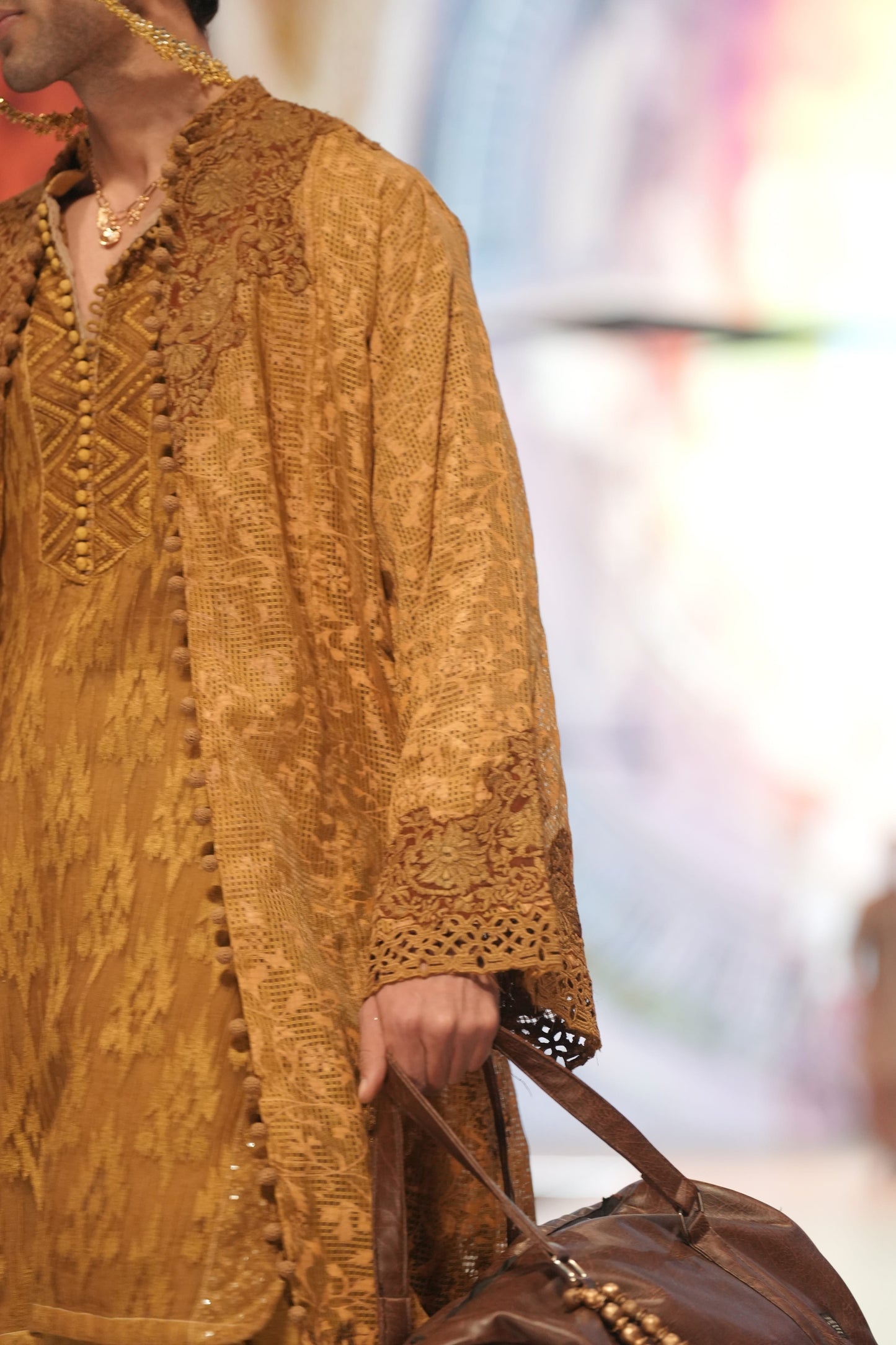 Man wearing a patterned mustard yellow kurta with a blurred background