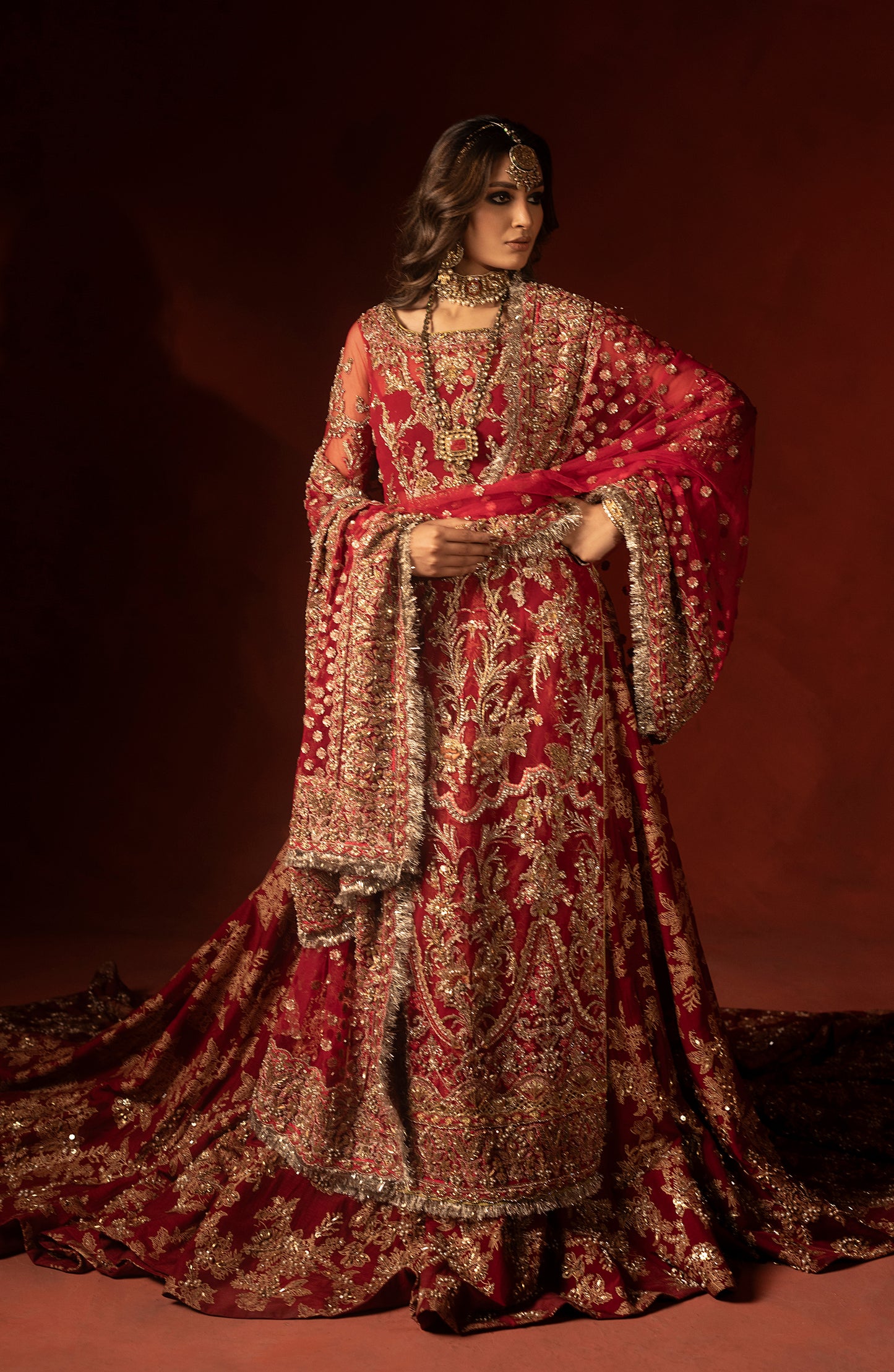 Full view of raspberry red lehenga set with embroidered trail
